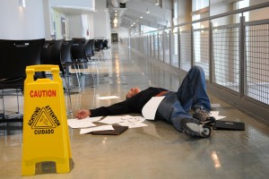 Man lies on the wet floor on which he slipped in spite of caution sign selective focus on man's chin